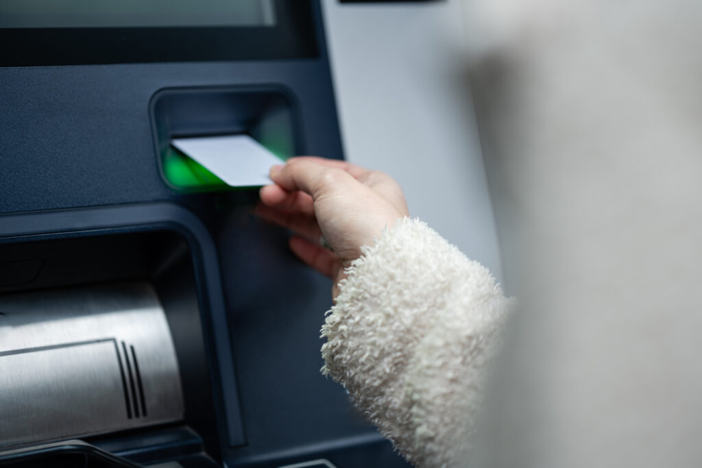 Hand placing a bank card into an automatic teller machine for a transaction, showing financial services and banking