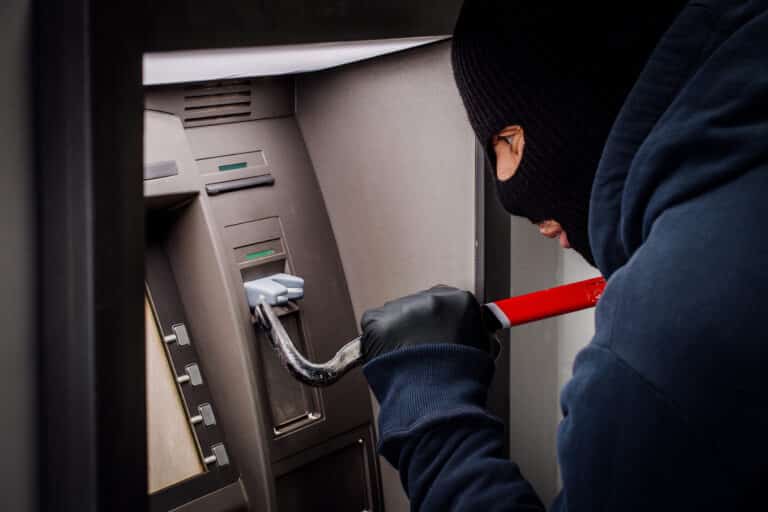 thief with crowbar opens the ATM.